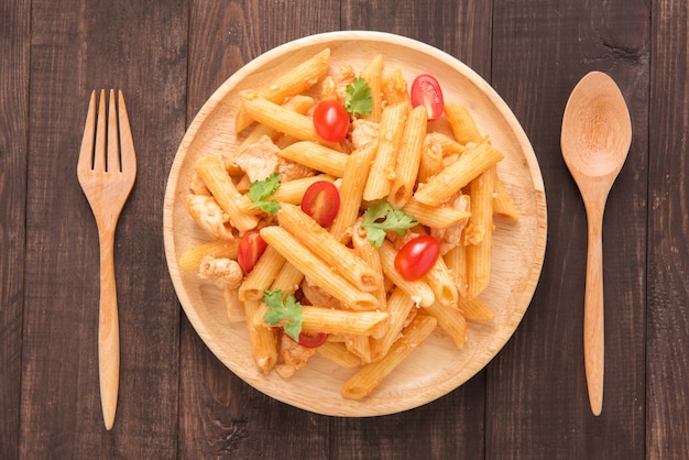 Pasta di Penne in salsa al pomodoro con il pollo su una tavola di legno