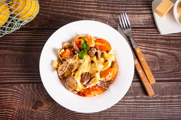 Pasta di pesce tradizionale italiana su piatto bianco con vongole alle vongole con pomodori e basilico Cibo gustoso e delizioso