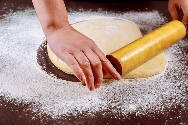 Pasta di rotolamento della donna con il mattarello per fare i panini.