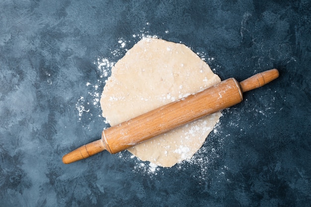 Pasta di rotolamento su una tabella con un mattarello di legno