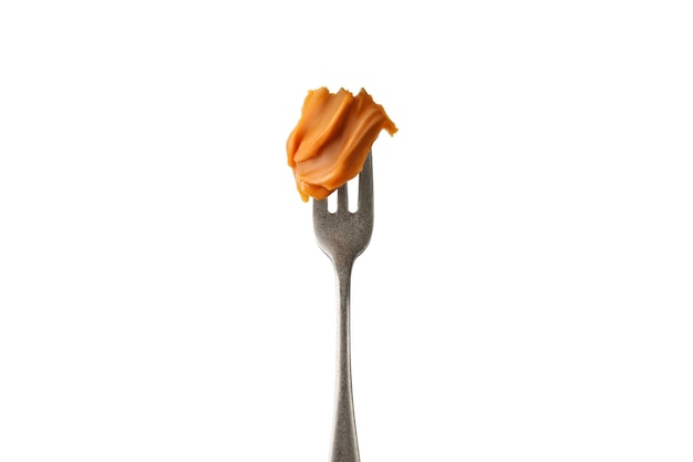 Pasta di sciroppo di caramello fuso liquido su una forchetta isolata su uno sfondo bianco Onda arricciata di caramello