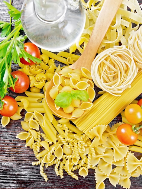 Pasta diversa con olio e pomodori su tagliere scuro