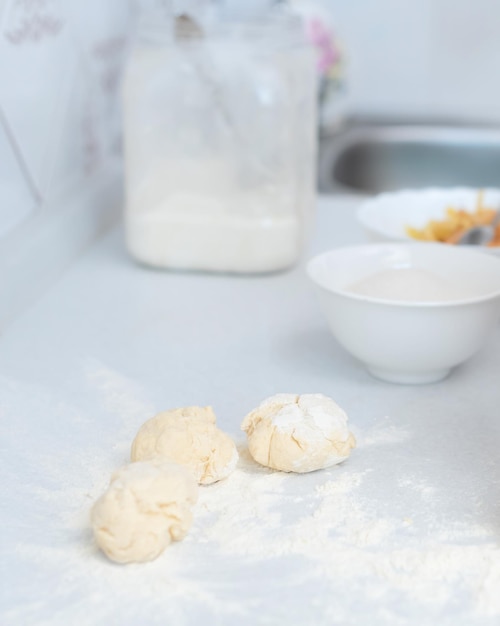 Pasta e farina sul tavolo da cucina bianco con mela grattugiata sfocata e zucchero sullo sfondo