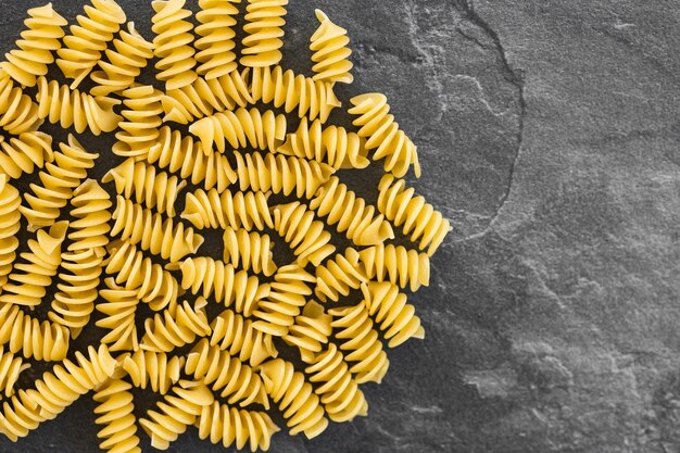 Pasta eliche cruda isolata su sfondo scuro con tracciato di ritaglio