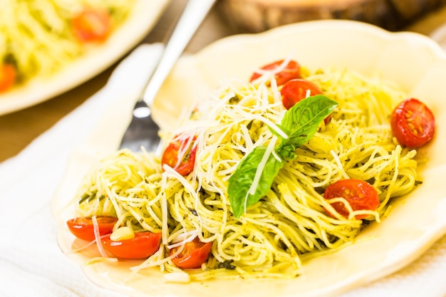 Pasta fatta in casa capelli d'angelo con pesto e pomodorini arrostiti.