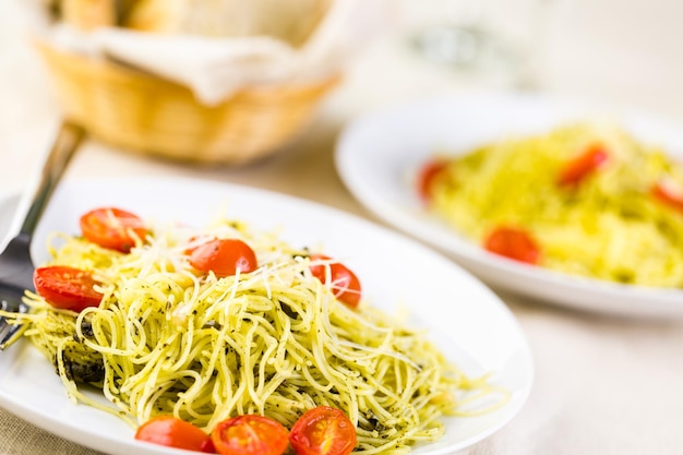 Pasta fatta in casa capelli d'angelo con pesto e pomodorini arrostiti.