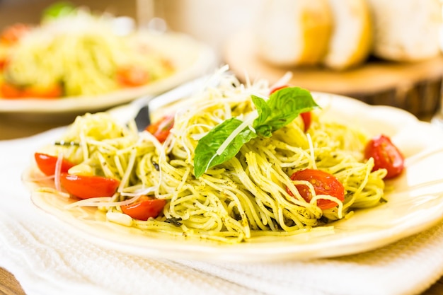 Pasta fatta in casa capelli d'angelo con salsa al pesto e pomodorini arrostiti.