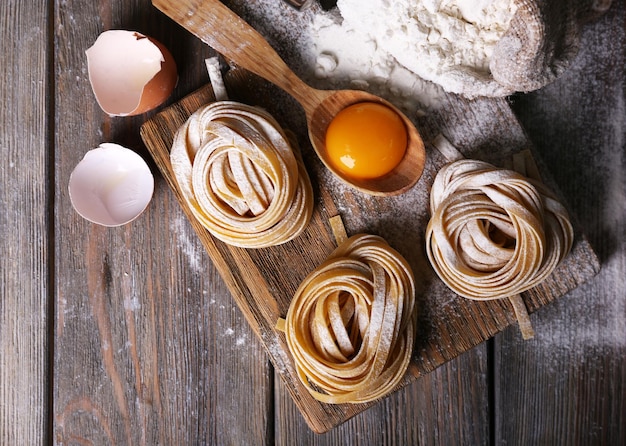 Pasta fatta in casa cruda e ingredienti per pasta su fondo di legno