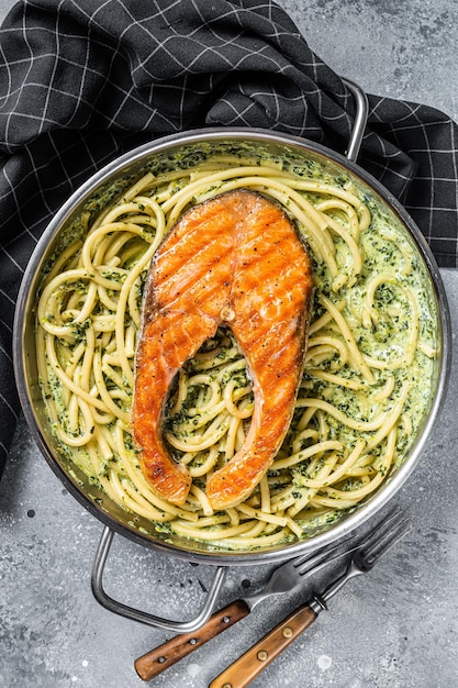 Pasta fiorentina con salsa cremosa di spinaci e trancio di salmone grigliato Sfondo grigio Vista dall'alto