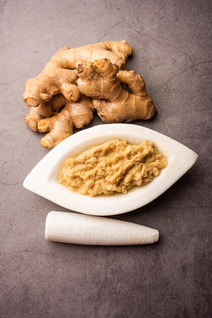 Pasta fresca allo zenzero o purea in una ciotola e intero Adrak su sfondo lunatico, fuoco selettivo