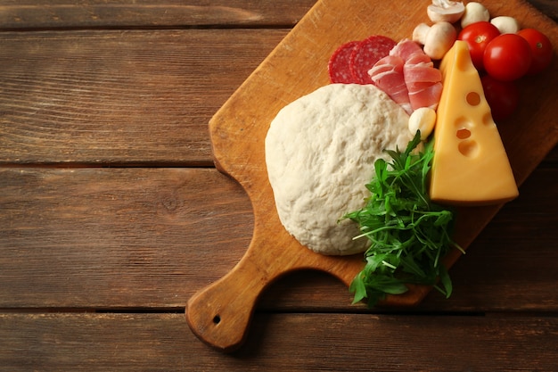 Pasta fresca e altri ingredienti diversi per la pizza su fondo in legno