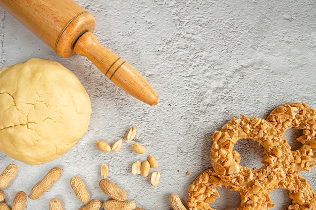 Pasta frolla biscotto, mattarello, arachidi e biscotti sul tavolo della cucina.