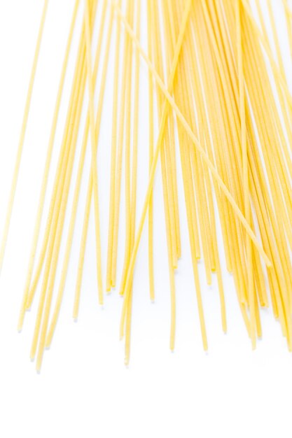 Pasta gialla organica degli spaghetti su un fondo bianco.