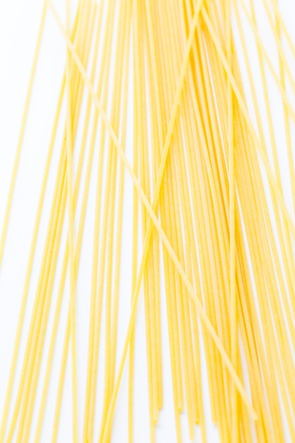 Pasta gialla organica degli spaghetti su un fondo bianco.