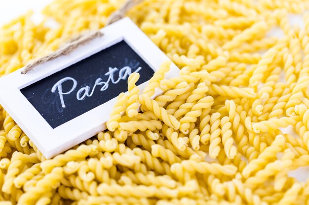 Pasta gialla organica dei gemelli su un fondo bianco.