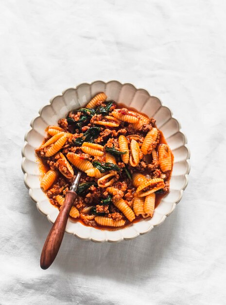 Pasta gnocchetti con salsa bolognese e spinaci su uno sfondo chiaro vista dall'alto delizioso cibo confortevole