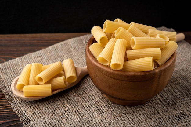 Pasta in ciotola di legno su fondo di legno.