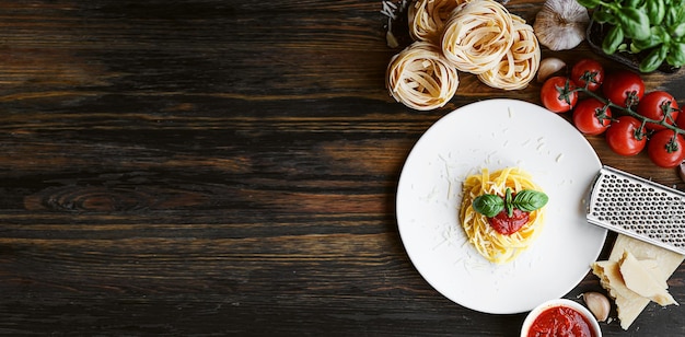 Pasta italiana alla bolognese con parmigiano grattugiato e basilico closeup ingredienti in background