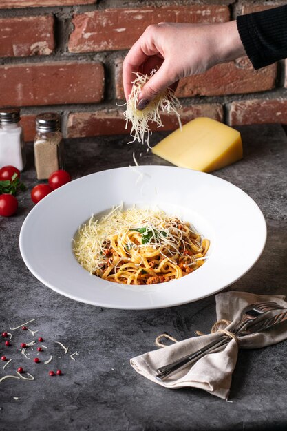 Pasta italiana alla bolognese su un piatto bianco con ingredienti su un menu del ristorante di sfondo scuro