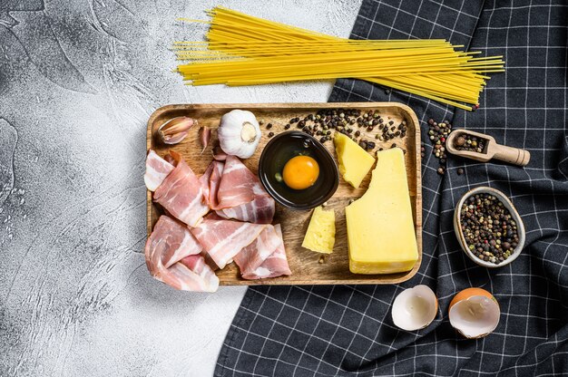 Pasta italiana alla carbonara Ingredienti. Pancetta, spaghetti, parmigiano e pecorino, uovo, aglio. Sfondo grigio. Vista dall'alto