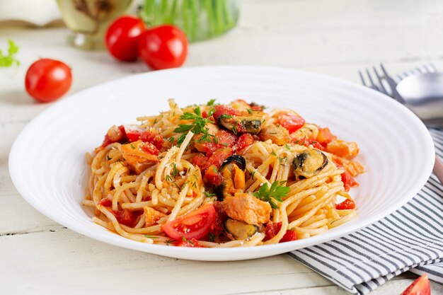 Pasta italiana classica spaghetti marinara con cozze e salmone su tavola bianca spaghetti pasta con salsa marinara