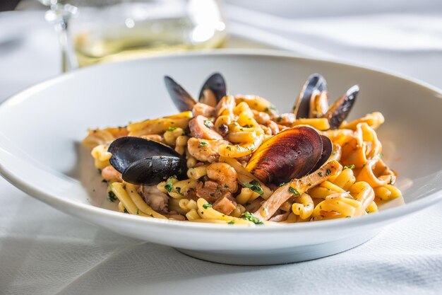 Pasta italiana con cozze e gamberi in piatto bianco