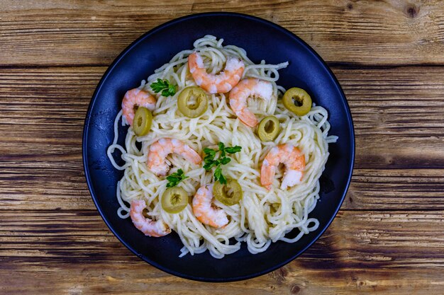 Pasta italiana con gamberi e olive in un piatto nero Vista dall'alto