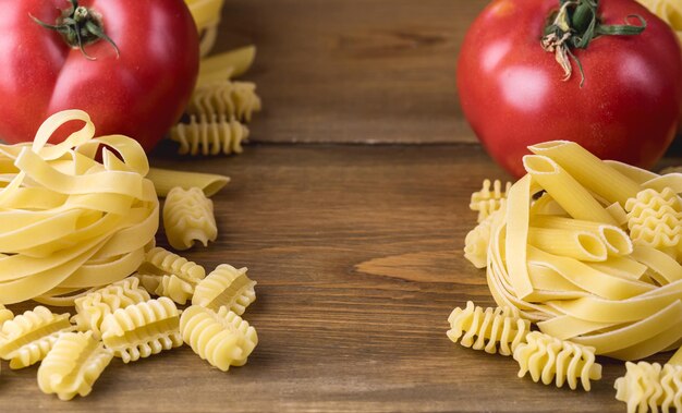 Pasta italiana con pomodori su fondo in legno Cibo italiano Cornice per cena Posto per testo