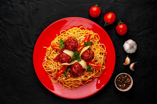 Pasta italiana con salsa al pomodoro e polpette in un piatto con le spezie sulla pietra