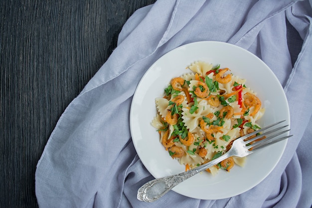 Pasta italiana con salsa con i gamberi su una zolla, vista superiore. Legno scuro. .