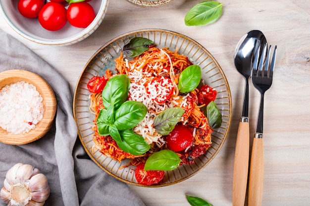 Pasta italiana con salsa di pomodoro pomodori formaggio e basilico su sfondo chiaro