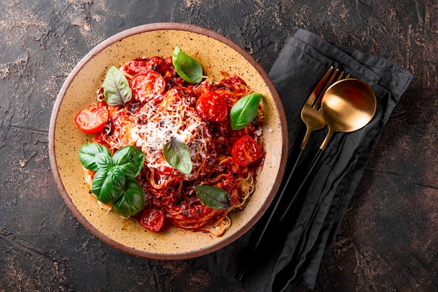 Pasta italiana con salsa di pomodoro pomodori formaggio e basilico su sfondo scuro vista dall'alto