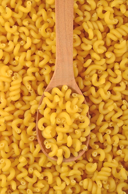 Pasta italiana cruda in un cucchiaio di legno