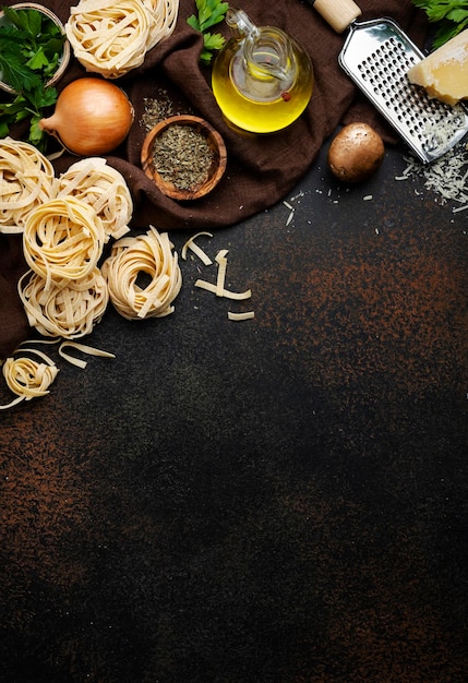 Pasta italiana cruda marrone champignon funghi verdure formaggio e ingredienti per una gustosa cucina sul vecchio tavolo da cucina sfondo stile scuro vista dall'alto Banner alimentare