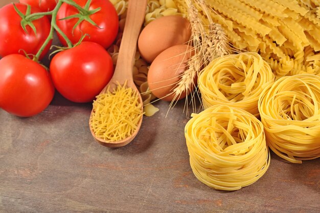 Pasta italiana cruda, ramo di pomodori maturi e uova