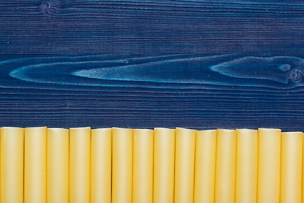 Pasta italiana cruda sulla vista di legno e superiore blu scuro