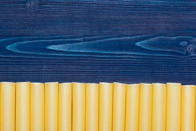 Pasta italiana cruda sulla vista di legno e superiore blu scuro