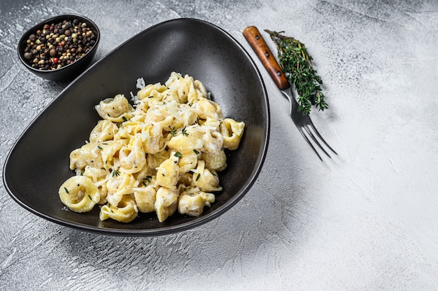 Pasta italiana dei tortellini in salsa di panna con spinaci. Vista dall'alto.