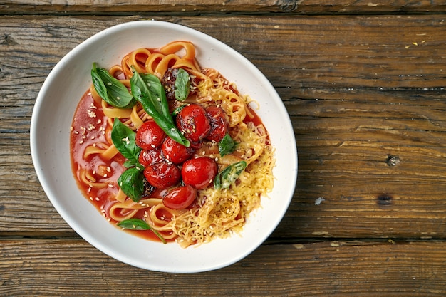 Pasta italiana e casalinga - spaghetti con i pomodori e formaggio in una ciotola su un di legno