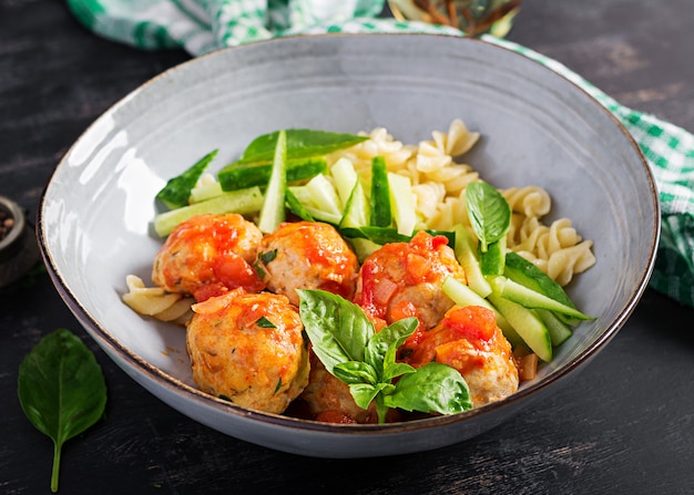 pasta italiana. Fusilli con polpette, cetriolo e basilico su sfondo scuro. Cena. Concetto di cibo lento.