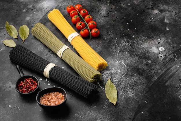 Pasta italiana secca colorata su sfondo nero tavolo in pietra scura con spazio per la copia del testo