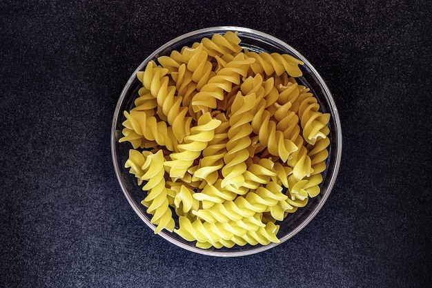 Pasta italiana su una lastra di vetro. Sfondo nero. Concetto pubblicitario con copia spazio per testo personalizzato.