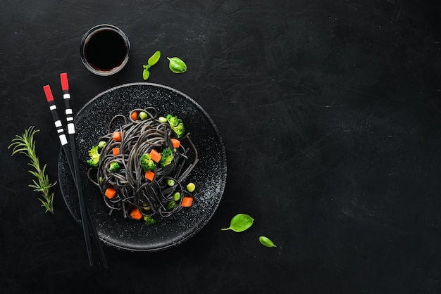 Pasta nera con verdure su piatto nero Vista dall'alto su sfondo nero Spazio per la copia gratuito