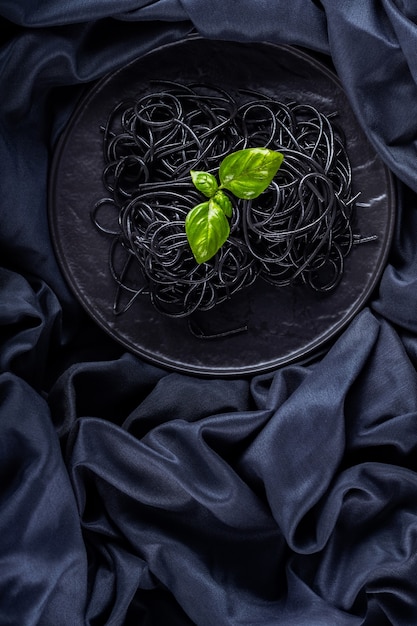 Pasta nera e basilico su fondo scuro