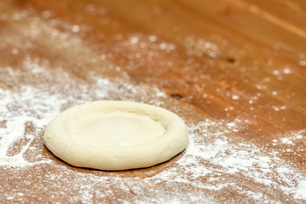 Pasta per pizza Base per cuocere la pizza su un primo piano di un tavolo di legno