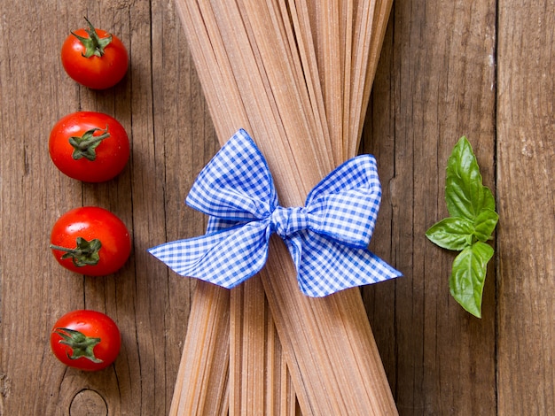 Pasta, pomodori e basilico degli spaghetti sulla vista superiore del fondo di legno