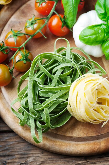 Pasta, pomodoro e basilico crudi sulla tavola di legno