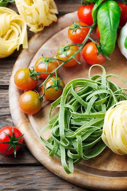 Pasta, pomodoro e basilico crudi sulla tavola di legno