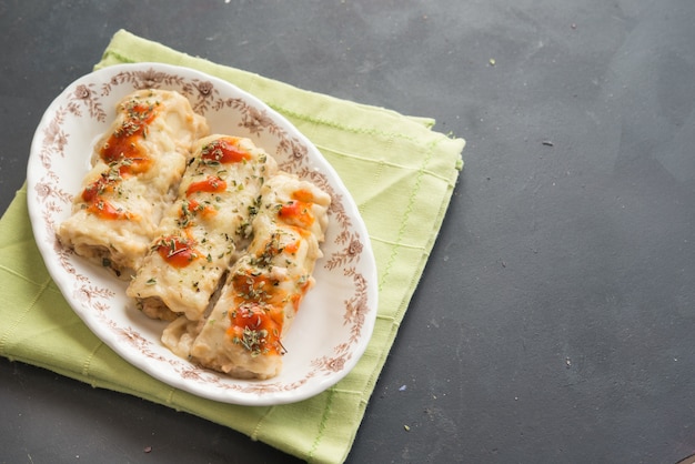 Pasta ripiena di carne su un piatto. Cannelloni italiani, canelones spagnoli con tovagliolo verde