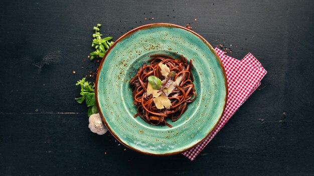 Pasta scura con parmigiano Cucina italiana su sfondo di legno Spazio per la copia gratuito Vista dall'alto